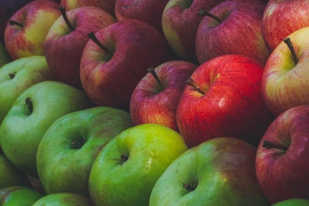 Photo en gros plan de plusieurs pommes. Les pommes du bas sont vertes et celles du haut sont rouge.