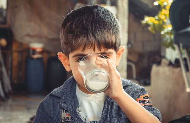 Petit garçon qui boit un verre de lait.